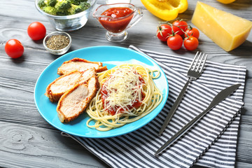 Tasty pasta with chicken parmesan slices on plate