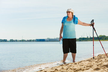 Senior woman practicing nordic walking on beach