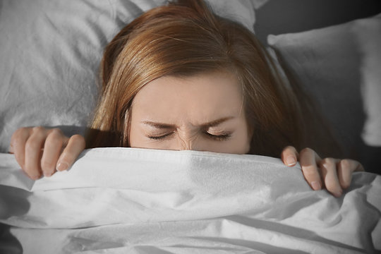 Young Scared Woman Hiding Under Blanket While Lying In Bed At Home