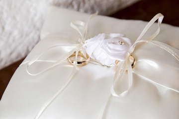 Anelli d'oro legati sopra cuscinetto bianco