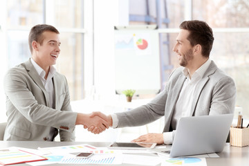 Businessmen shaking hands in office © Africa Studio