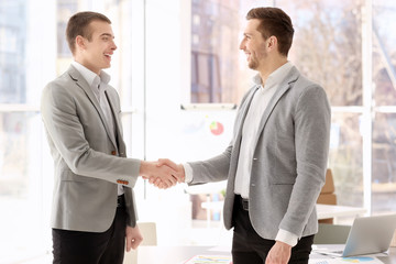 Businessmen shaking hands in office © Africa Studio