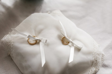 Anelli d'oro legati sopra cuscinetto bianco legati delicatamente