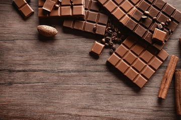 Chocolate bars with coffee beans on wooden background