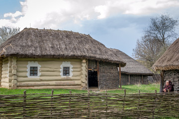 Fototapeta na wymiar National Museum Pirogovo in the outdoors near Kiev. Ancient peasant Ukrainian house with a thatched roof, spring landscape in the old village of national architecture, Ukraine.
