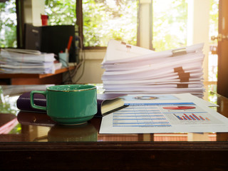 Close up of a cup of coffee and office supplies on desk in office at morning, warm tone