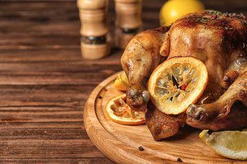 Homemade baked chicken with lemon on wooden board