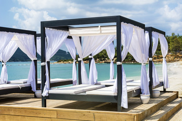 luxury sunbeds with white curtains on a pier in the sea .Summer holiday concept