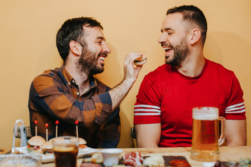 .Two male friends watching football in a bar, having beer and something to eat having a good time. Lifestyle portrait