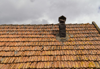 Ceramic tiles on roof of old hut with tin chimney