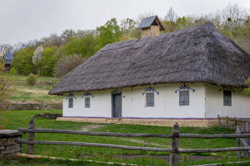 Fototapeta na wymiar National Museum Pirogovo in the outdoors near Kiev. Ancient peasant Ukrainian house with a thatched roof, spring landscape in the old village of national architecture, Ukraine.