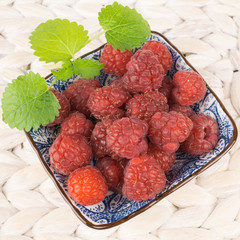 Kleine Schale mit frischen Himbeeren, Zitronenmelisse als Dekoration, quadratisch