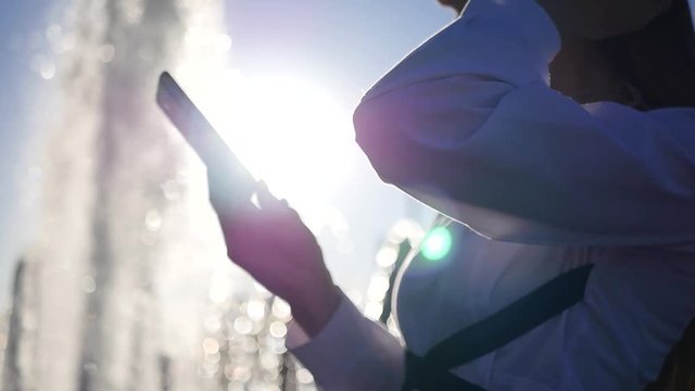 The girl is waiting for a meeting at the fountain, holding the phone in her hands, waiting for the call. SLOW MOTION. HD, 1920x1080.
