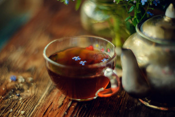 flower tea and a bouquet of forget-me-nots on a wooden background