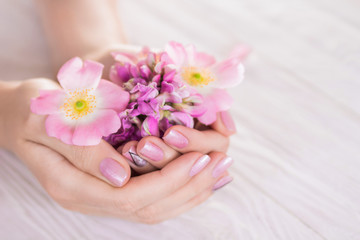 Obraz na płótnie Canvas Woman with pink manicure holds flowers