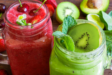 Freshly blended green and red smoothies in glass jars on rustic wooden background