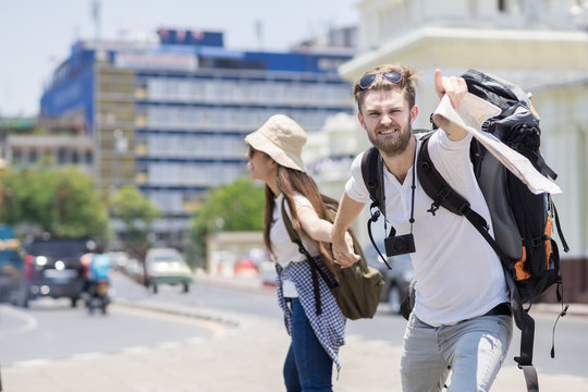 A traveler man is pulling woman's arm and point finger to forword at side road. Action traveling concept
