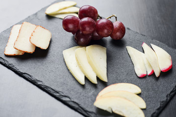 gourmet mixed cheese board tapas starter with apple and grapes