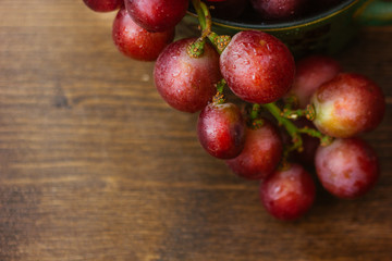 bunch of grapes on ceramic bowl over the wooden background