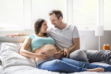 Obraz premium Young parents in bed expecting a little baby, Romantic moments for pregnant couple