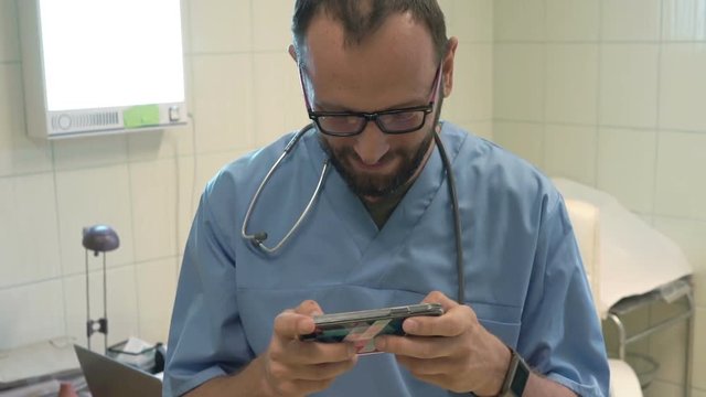Male doctor playing game on smartphone in office
