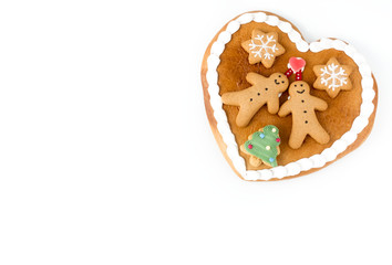 Close up of a cute Gingerbread heart decorated with Gingerbread Men, Gingerbread Stars and a Christmas Tree Cookie on white background with lots of copy space. 