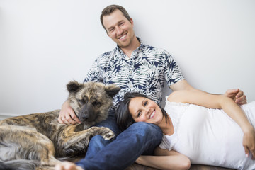 man sitting on floor with his dog and pregnant girlfriend