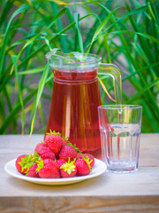 glass with strawberry juice and berries isolated on blur background