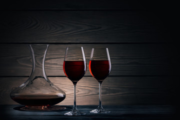 Two glasses and decanter of red wine on dark background
