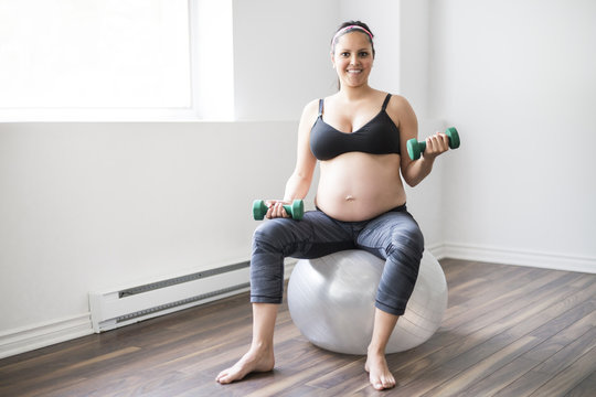 Pregnant woman training with dumbbells to stay active © pololia