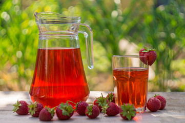 glass with strawberry juice and berries isolated on blur background