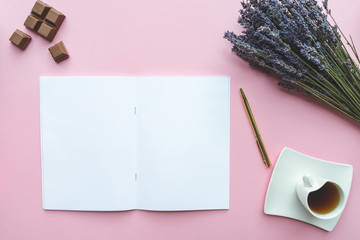 White empty notebook, pencil, lavanda flowers and cup of coffee on pink background. Feminine workspace, flat lay.