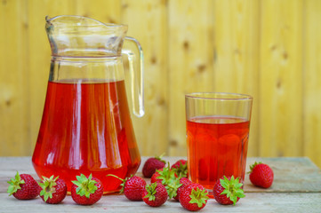 glass with strawberry juice and berries isolated on blur background