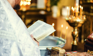 Baptism priest reading from bible during ceremony holding cross.Priest holds the Bible at the ceremony of Baptism.