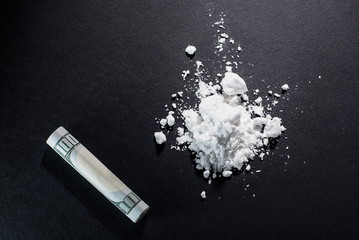Cocaine and a folded hundred-dollar bill on a black background