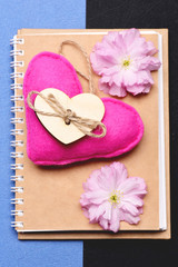 Heart in pink colour and pink sakura on beige notebook