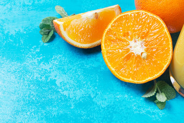 Orange slices with mint leaves on blue wooden background with copy space
