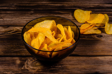 Potato chips in glass bowl on wooden table