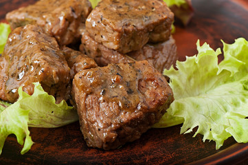 Freshly prepared juicy stewed veal with spicy sauce decorated with lettuce leaves.