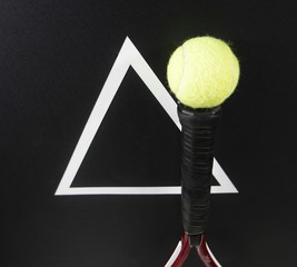 Tennis racket with a ball on a black background