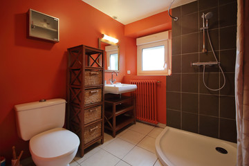 salle de bain avec douche et mur coloré en rouge orange