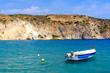 Fototapeta na wymiar Boat in a picturesque bay with crystal blue water, Firopotamos village, Milos, Cyclades Islands, Greece.