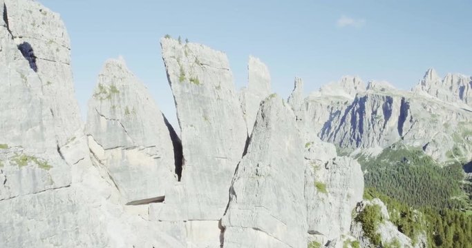 Aerial flight above mountain top with pines and rocks in sunny day. Summer adventure journey in mountain nature outdoors. Travel exploring Alps, Dolomites,Cinque Torri, Italy. 4k drone forward video