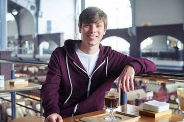 Male with nice hairstyle sitting over cup of coffee