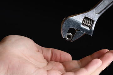Mens right hand outstretched catches of spanner nut wrench closeup