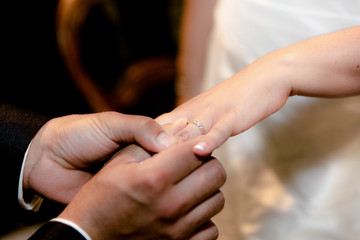 Close-up hands of bride and groom putting on a wedding rings