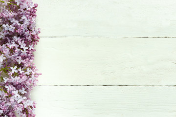 Bouquet of lilac flowers on white wooden background.