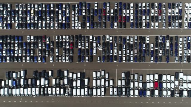Aerial top down view flying to right over new car storage parking lot showing imported new vehicles or ready to export new automobiles storage facility car industry for American and European market 4k