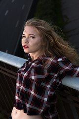 Girl in a plaid shirt. A blonde in a checked shirt on the street is leaning on a railing, close-up.