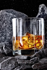 Glass of whiskey and ice.Creative photo glass of whiskey in stone mountain.Copy space.Advertising shot